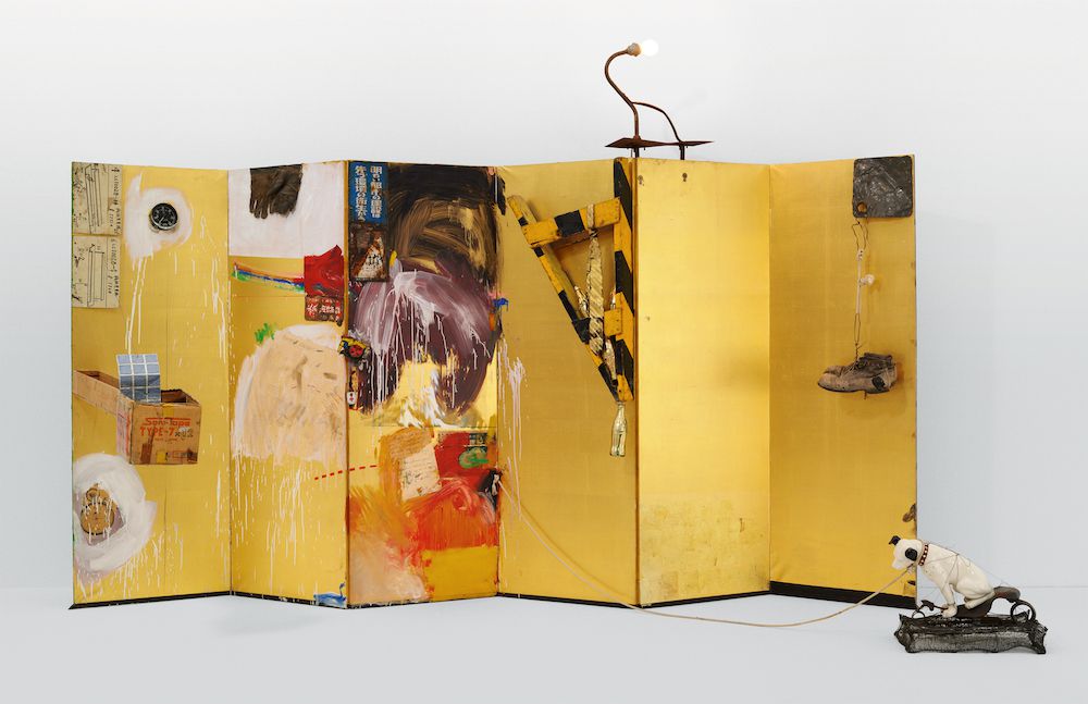 Robert Rauschenberg. Gold Standard. 1964. Oil, paper, printed reproductions, clock, cardboard box, metal, fabric, wood, string, pair of men’s boots, and Coca-Cola bottles on gold folding Japanese screen, with electric light, rope, and ceramic dog on bicycle seat and wire-mesh base, 7 ft. 1/4 in. × 11 ft. 10 1/8 in. × 51 1/4 in. (214 × 361 × 130.2 cm). Glenstone Museum. Photograph: Tim Nighswander/Imaging4Art.com. © 2017 Robert Rauschenberg Foundation<br/>